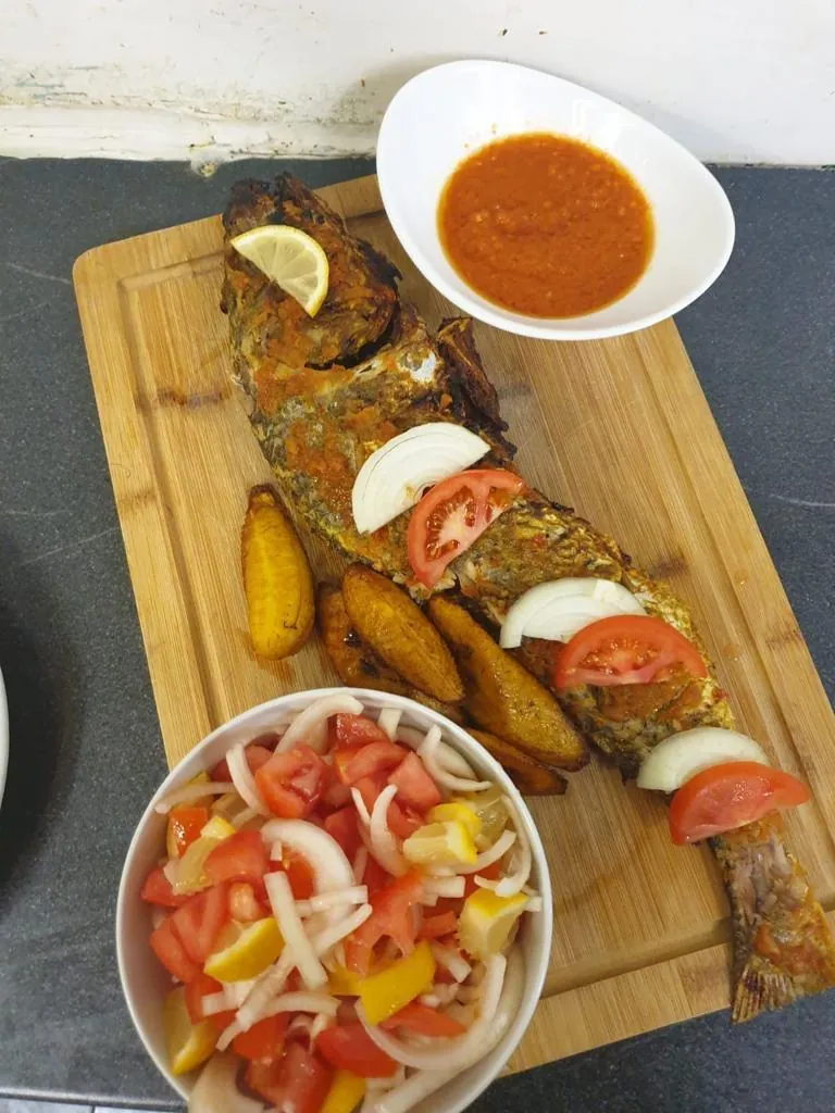 Whole grilled fish with plantain, salad and sauce